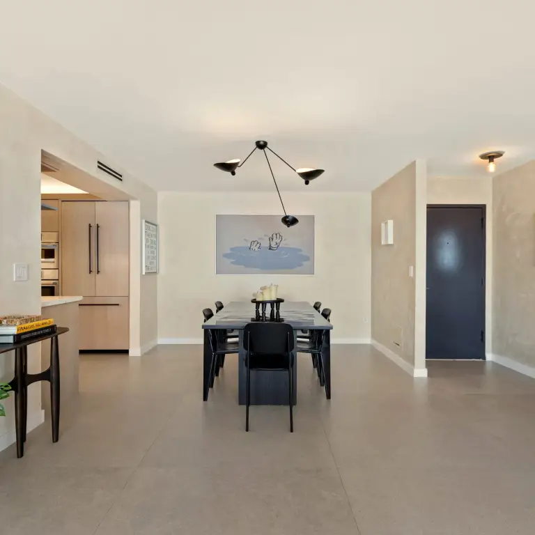 Dining area with dark wood table, black chairs and a three-arm pendant light at Costa Residence