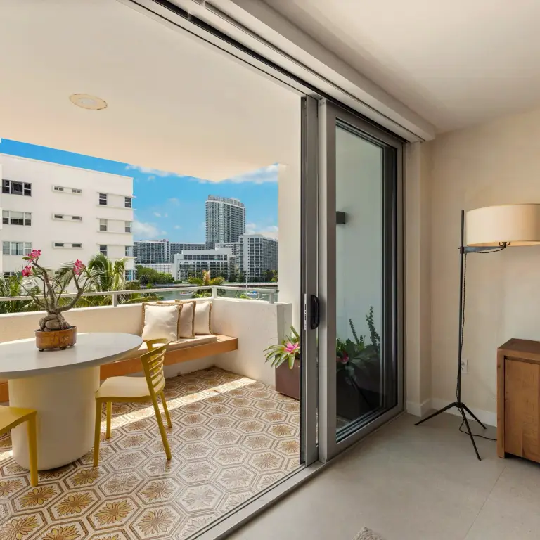 Balcony with patterned cement tile, café table and bench overlooking the Miami Beach skyline at Costa Residence