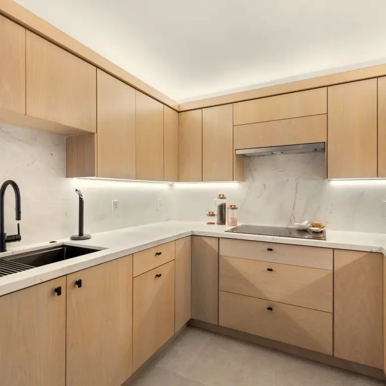 Kitchen detail with oak cabinetry, marble counters and integrated under-cabinet lighting at Costa Residence