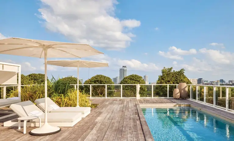 Rooftop pool deck with chaise lounges, umbrellas and city skyline