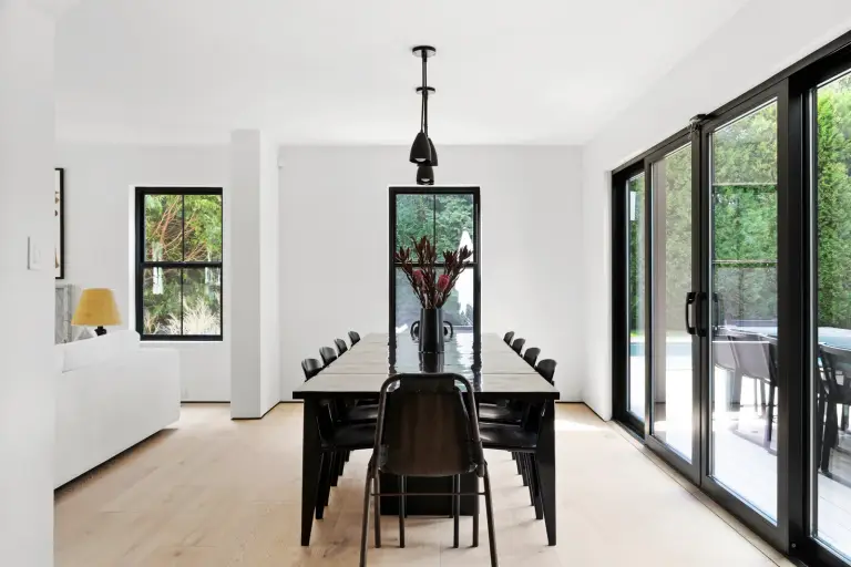 Dining room with a long black table for ten and a cone pendant light opening to the terrace at the Farmstead