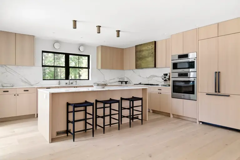 Kitchen with white oak flat-panel cabinetry, a marble waterfall island and brass pendant lights at the Farmstead