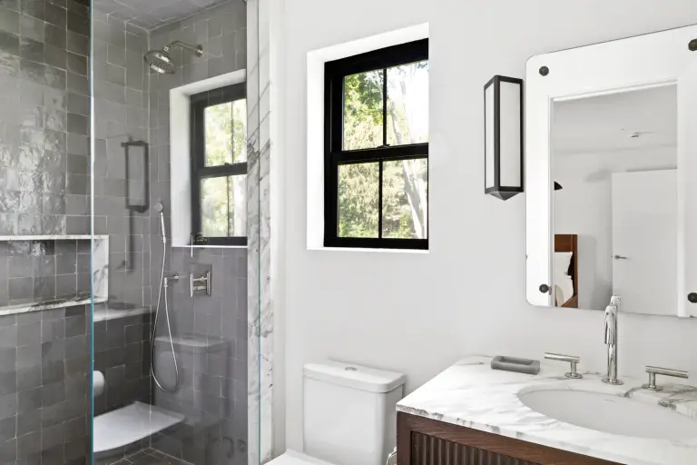 Bathroom with a grey zellige-tiled shower, floating bench and marble-topped walnut vanity at the Farmstead