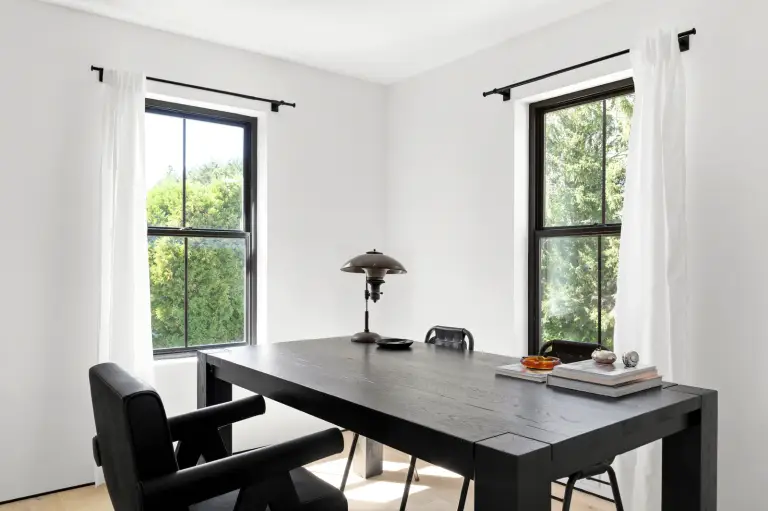 Study with a black oak trestle table, leather chairs and a brass desk lamp between twin windows at the Farmstead