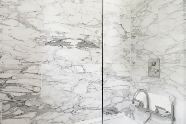 Marble-tiled shower with chrome wall-mounted fixtures at the Farmstead