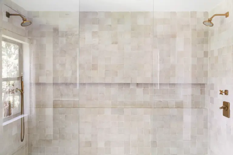 Zellige-tiled double shower with twin brass rain heads behind frameless glass at the Farmstead