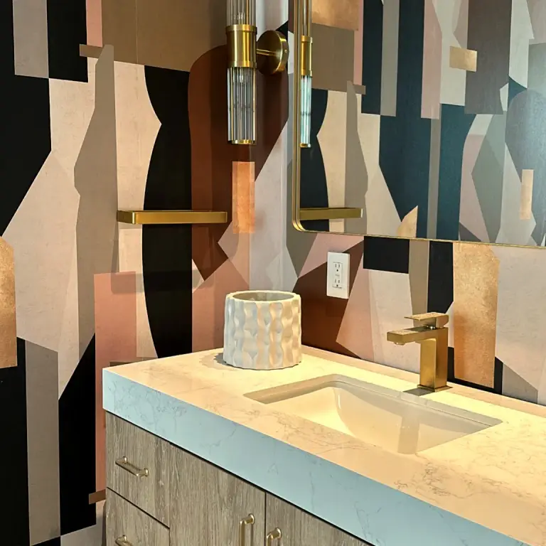 Powder room vanity with geometric wallpaper, brass sconce and brass faucet at Feit Residence