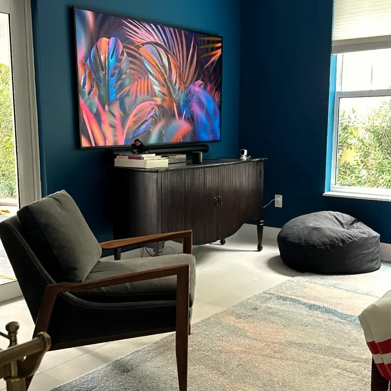 Media room with navy walls, wall-mounted TV and curved dark-wood credenza at Feit Residence