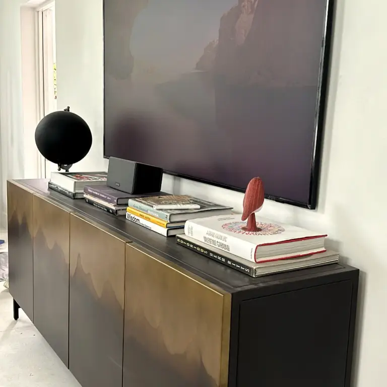 Dark walnut media console with books and a globe under a wall-mounted TV at Feit Residence