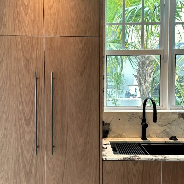 Floor-to-ceiling walnut cabinetry beside a black faucet and marble sink at Feit Residence
