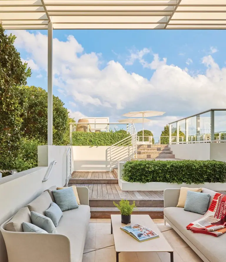 Rooftop terrace lounge with outdoor sofas, pergola and stairs up to the pool deck at Ritz Penthouse