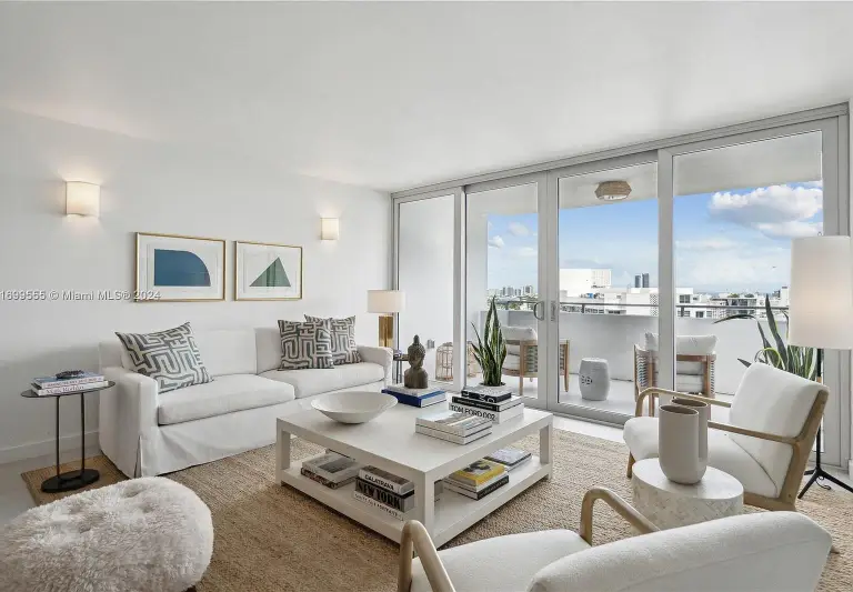 White living room with slipcovered sofa, coffee table books and sliding doors to the balcony at Silver Residence