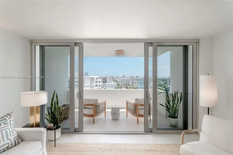 Living room opening through sliding glass doors to a balcony with cane chairs at Silver Residence