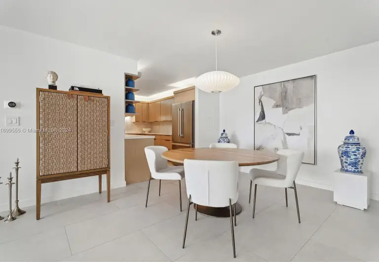 Dining area with round wood table, white chairs and a paper pendant light beside the kitchen at Silver Residence
