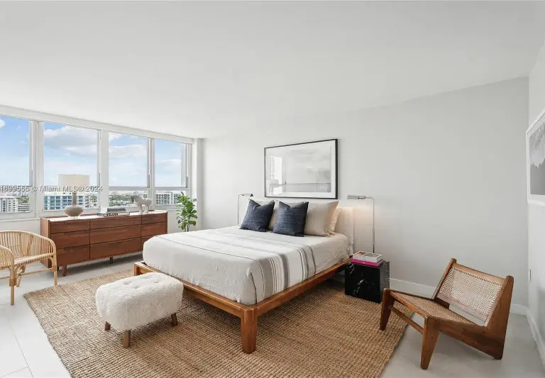 Bedroom with wood platform bed, black marble nightstand and city views through bay windows at Silver Residence