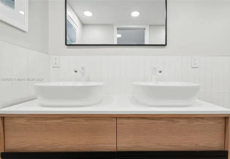 Double vanity with twin vessel sinks and oak cabinetry beneath a mirror at Silver Residence