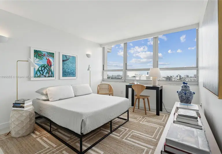 Guest bedroom with a metal-frame bed, colorful framed prints and a desk by bay windows at Silver Residence