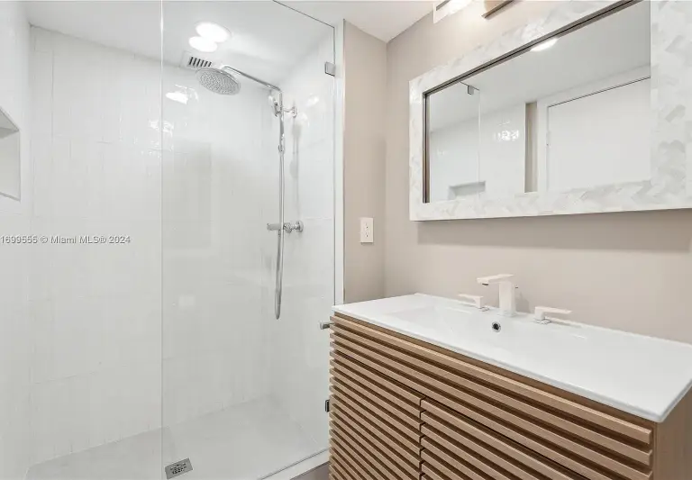 Bathroom with a ribbed oak vanity, integrated sink and frameless glass shower at Silver Residence