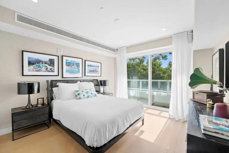 Bedroom with a cane-back bed, black nightstands and a gallery wall of framed photographs at Starr DeVos Condo