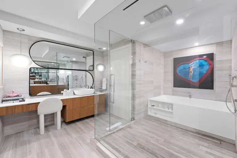 Bathroom with a vessel sink, oval black-framed mirror and sculptural stool at Starr DeVos Condo