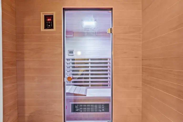 Cedar-clad sauna with a glass door and built-in bench at Starr DeVos Condo