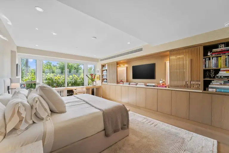 Bedroom with a built-in oak shelving and TV wall at Starr DeVos Condo
