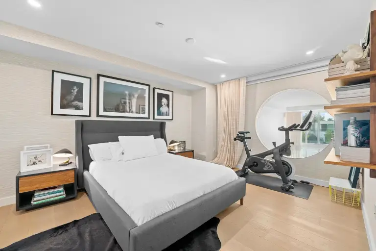 Bedroom with an upholstered bed, wood nightstand and framed prints on grasscloth walls at Starr DeVos Condo