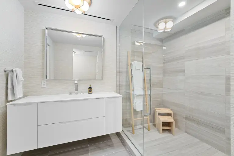 Spa bathroom with a floating vanity, wood-look porcelain tile and cedar stools beside a glass shower at Starr DeVos Condo