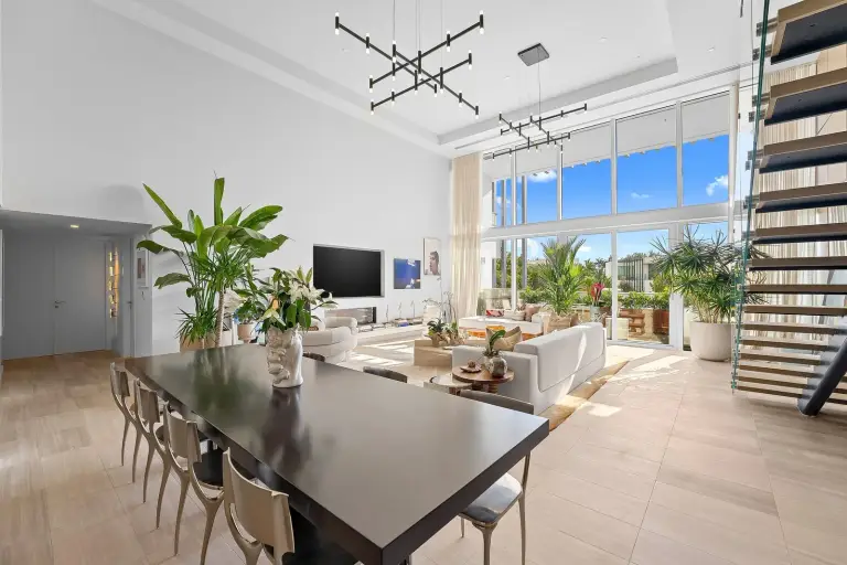 Double-height living and dining space with a sculptural chandelier and open-tread stair at Starr DeVos Condo