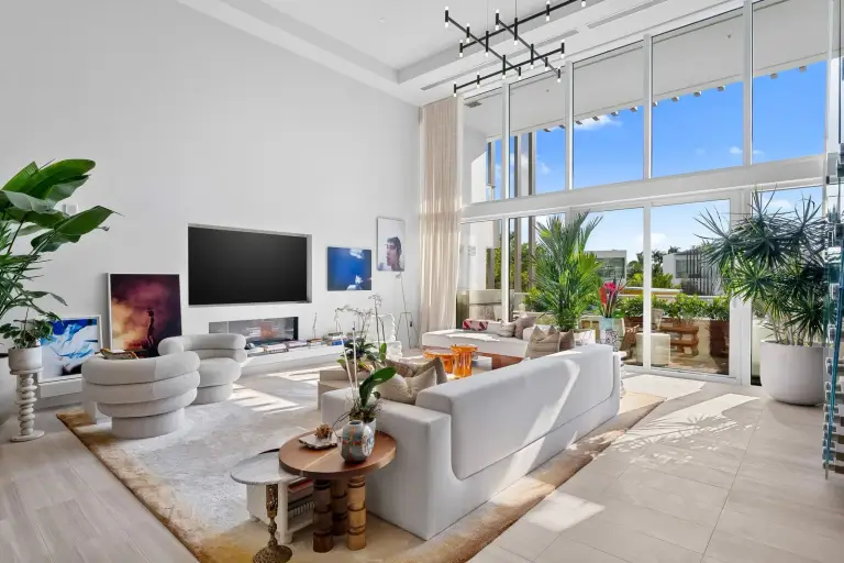 Living room with a cream sofa, channel-tufted swivel chair and terrace doors at Starr DeVos Condo