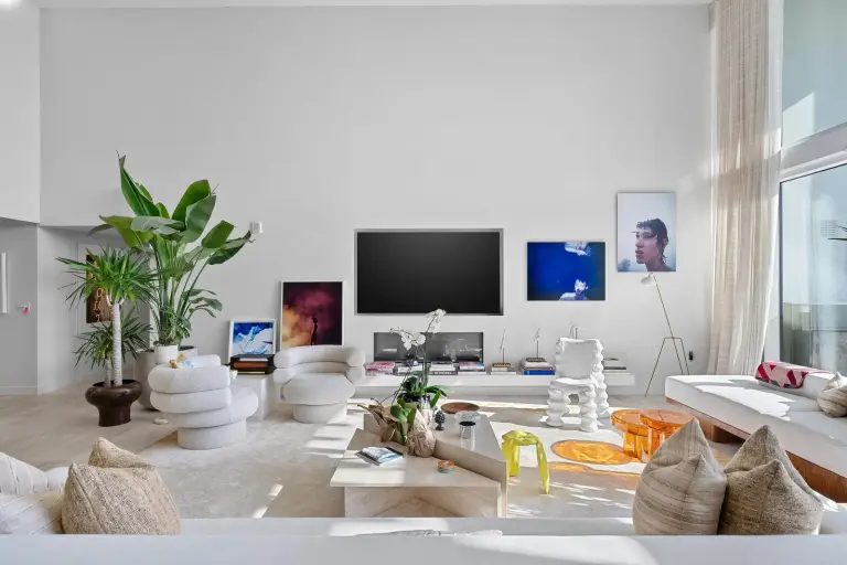 Living room with bouclé swivel chairs, a marble coffee table and contemporary art at Starr DeVos Condo