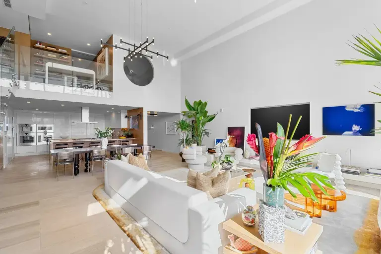 Open-plan living, dining and kitchen beneath a mezzanine study with oak bookshelves at Starr DeVos Condo