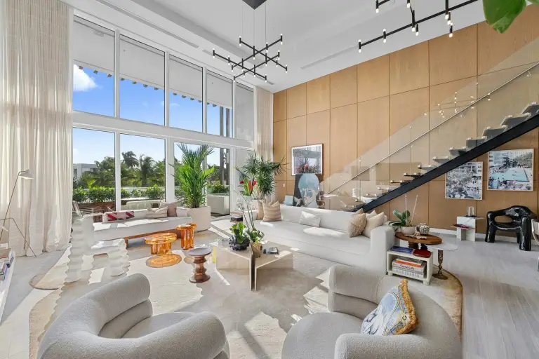 The Starr–DeVos residence's double-height living room, framed by a glass stair and warm oak paneling