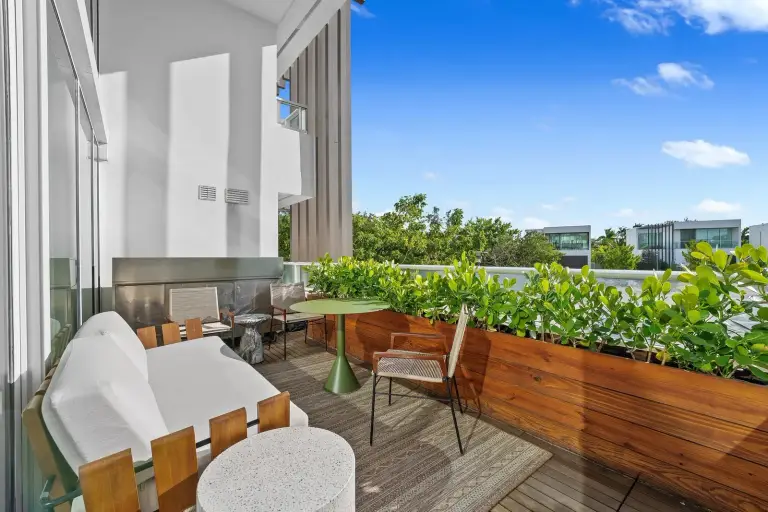 Terrace lounge with an outdoor sofa, woven chairs and a café table surrounded by planting at Starr DeVos Condo